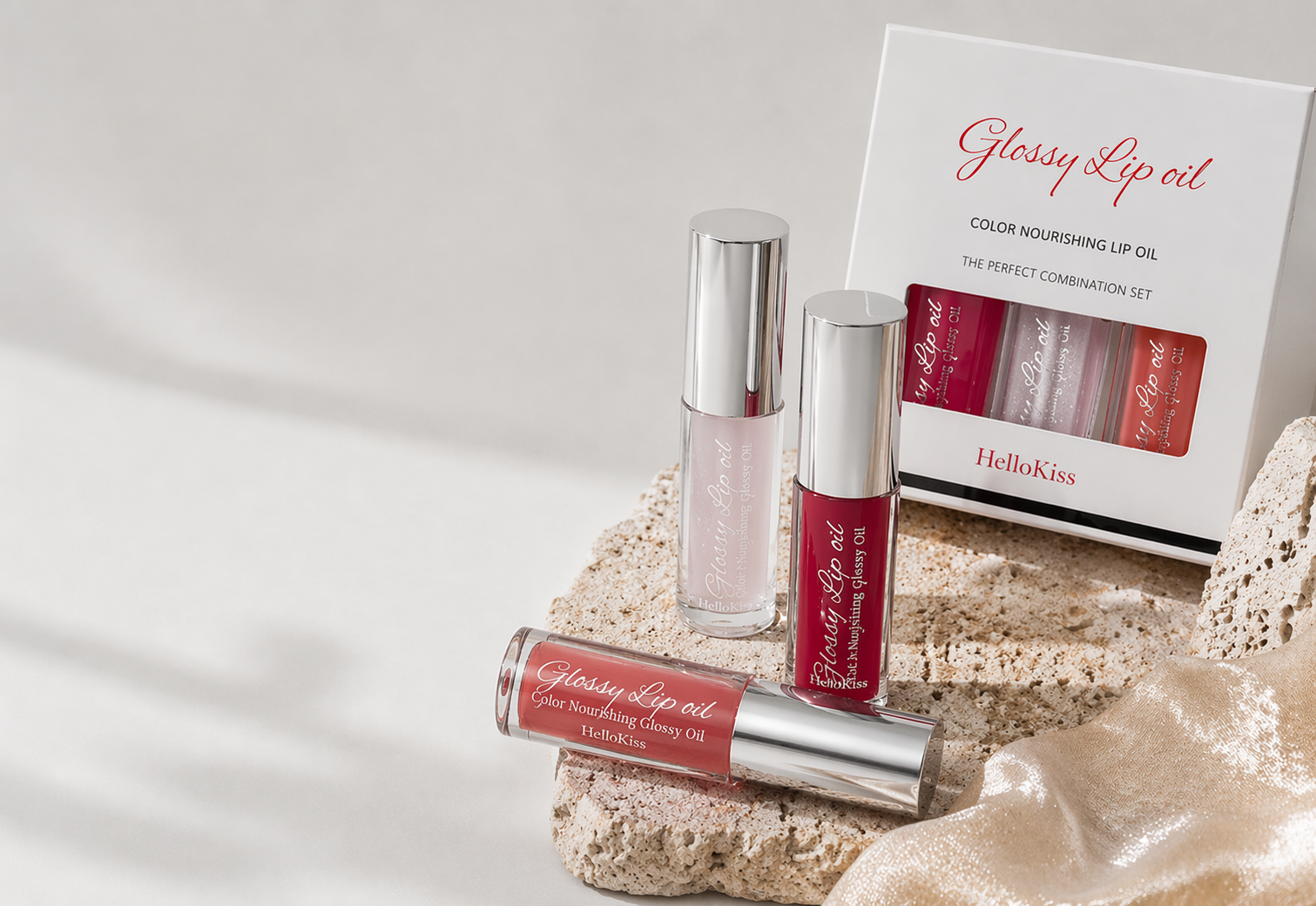 HelloKiss glossy lip oil set displayed in a minimal neutral beauty scene with soft lighting